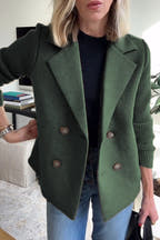 Person wearing a green coat with a blurred indoor background