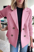 Person wearing a pink blazer with a blurred indoor background