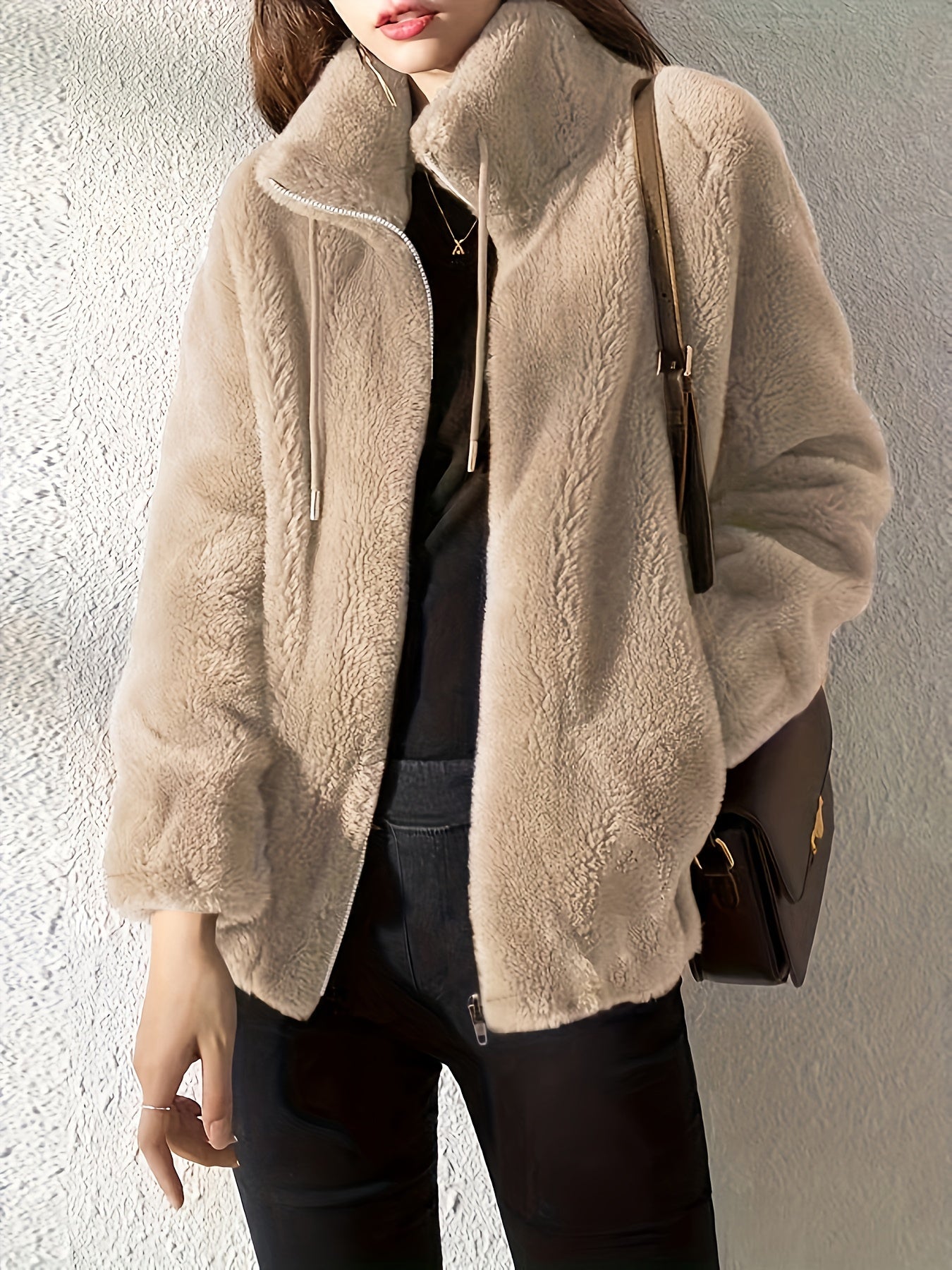 Person wearing a beige sherpa jacket with a neutral background